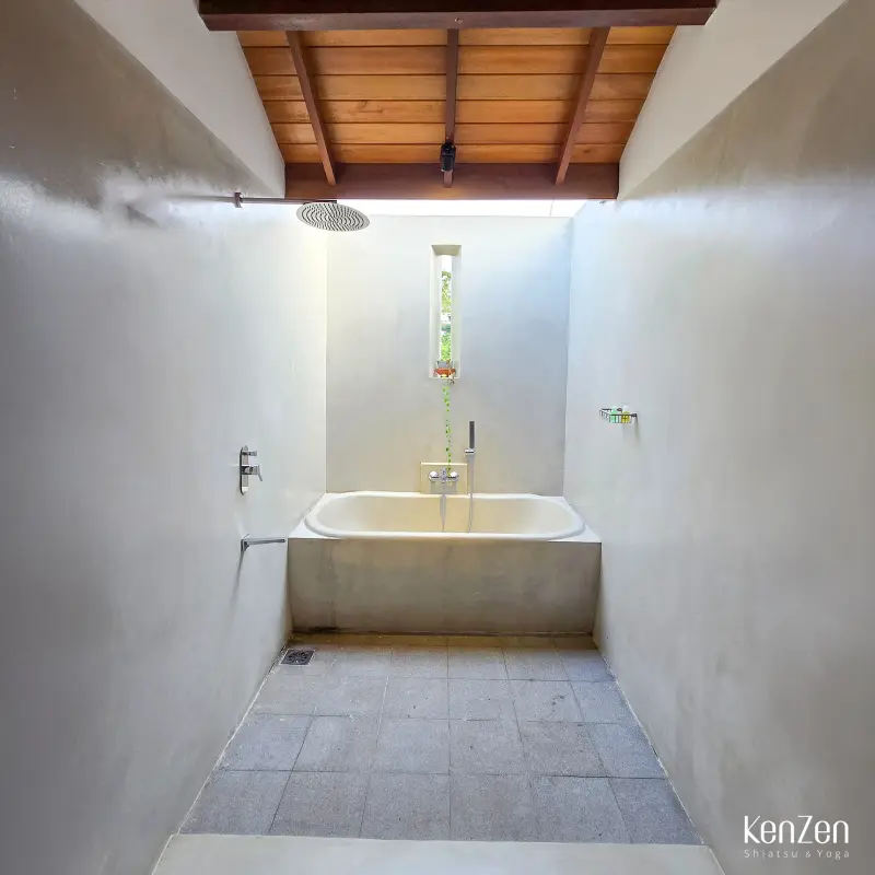 Baignoire à ciel ouvert et douche spacieuse dans la salle de bain de la suite Jasmin, avec rangements intégrés.